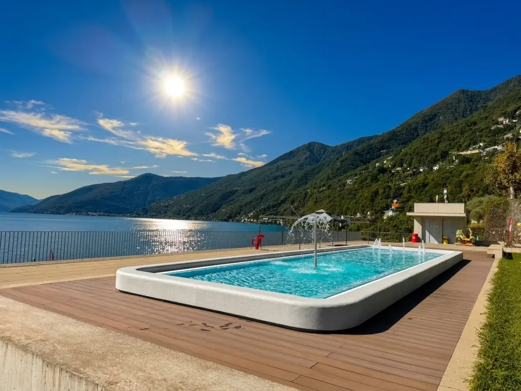Veduta aerea del Lido di Brissago con le sue piscine verdi, le aree relax e l'accesso al lago, circondato da vegetazione lussureggiante.